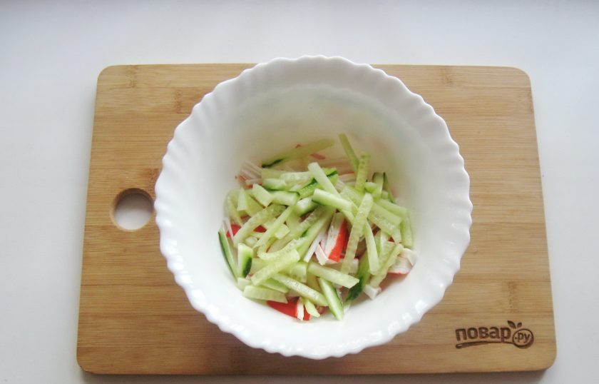 1. Этап. Салат с дайконом и крабовыми палочками: Свежий огурец также нарежьте соломкой и добавьте в салат.