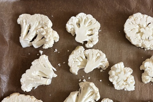 1. Этап. Цветная капуста, запечённая под моцареллой: Помыть капусту под проточной водой и нарезать шайбами толщиной 1,5 - 2 см. Уложить на противень, застеленный бумагой для выпечки.