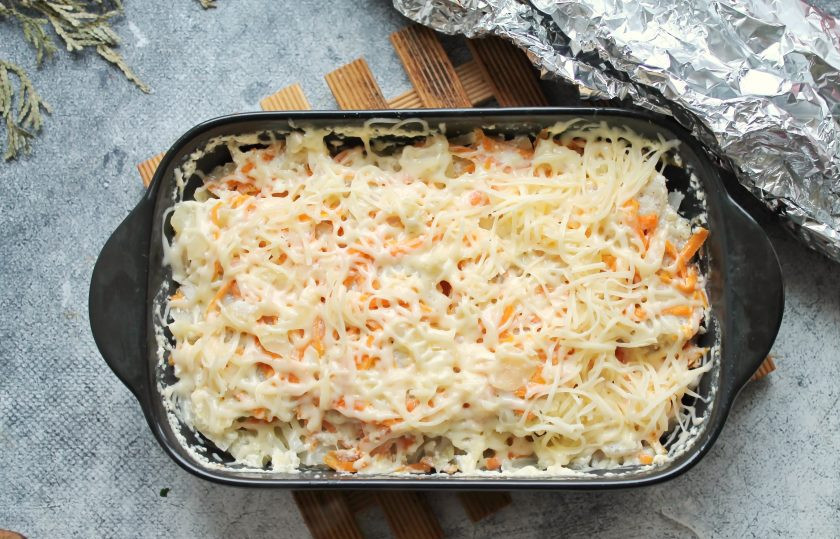 1. Этап. Треска с капустой: Твердый сыр натрите на средней терке. Форму с треской и капустой достаньте из духовки, уберите фольгу и посыпьте тертым сыром.