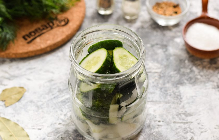 1. Этап. Огурчики по-болгарски на зиму: Подготовьте банки для заготовки. Тщательно вымойте с содой или специальным моющим средством. После стерилизуйте банки над паром, в духовке или микроволновке, как вам удобнее. Крышки также проварите в крутом кипятке 8-10 минут. Наполните банку слоями: огурцы, лук, чеснок.