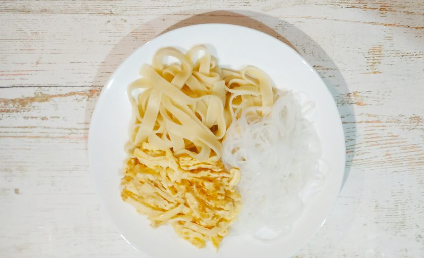 1. Этап. Ашлянфу: Начнем собирать наше блюдо. В глубокую посуду положите немного пшеничной и рисовой лапши, а также небольшое количество омлета.