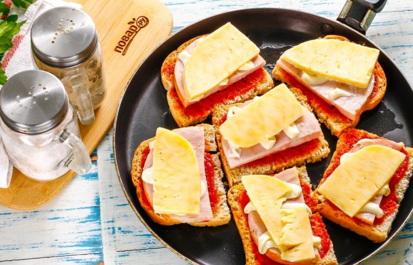 1. Этап. Бутерброды с ветчиной и сыром: Прогрейте сковороду с растительным маслом. Выложите в масло бутерброды и поджарьте их около 1-2 минут на умеренном нагреве. Затем влейте сбоку на сковороду воду и сразу же накройте емкость крышкой, нагрев уменьшите до минимального. Томите горячие бутерброды примерно 3-4 минуты, пока сыр не расплавится. Затем нагрев выключите.