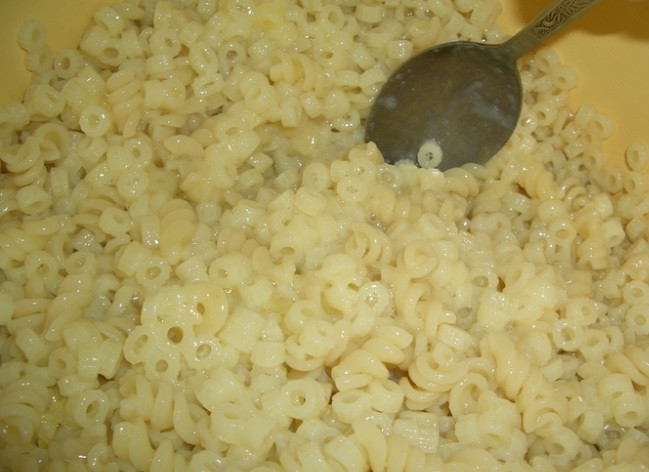 1. Этап. Запеканка из макарон со свининой: 2. Макароны отвариваем в подсоленной воде, откидываем на дуршлаг и перекладываем в миску. Вбиваем к ним яйцо и добавляем мелко рубленный чеснок.