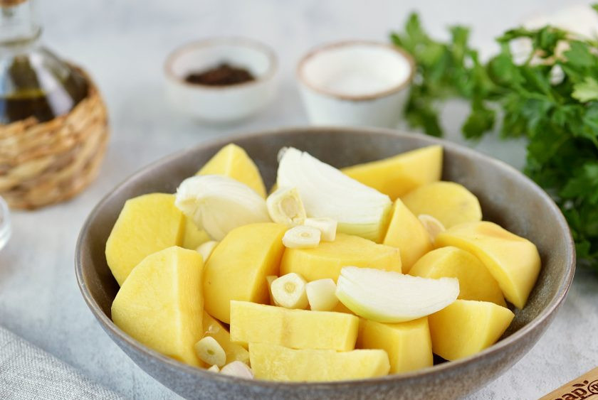 1. Этап. Телячья ножка с овощами в духовке: Картофель и лук нарежьте дольками, измельчите чеснок, переложите овощи в глубокую миску.