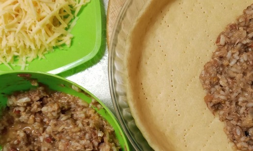 1. Этап. Пирог с консервированным тунцом: Тесто достать из холодильника, убрать пищевую пленку, дно в нескольких местах наколоть вилкой, отправить выпекаться в предварительно разогретый до 180 градусов духовой шкаф на 10 минут. Пассерованные овощи смешать с отваренным рисом и взбитыми яйцами. Из духового шкафа достать слегка подпеченное тесто, распределить начинку, не выходя за бортики. Присыпать тертым сыром и запекать в духовке в течение 40 минут при 180 градусах.