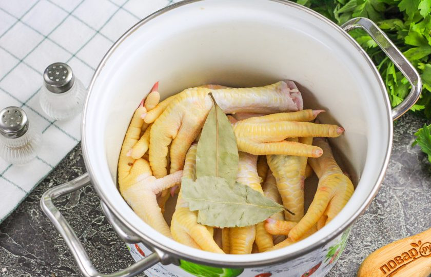 1. Этап. Закуска из куриных лапок: Выложите их в кастрюлю, всыпьте приправу куриную, 2 щепотки соли и лавровые листья. Залейте горячую воду и отварите лапки 20 минут.