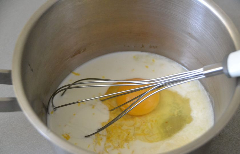 1. Этап. Лимонные эклеры: Первым делом займитесь приготовлением заварного крема. Для этого влейте в сотейник 125 мл. молока и сок одного лимона. Добавьте цедру 1 лимона, вбейте яйцо, размешайте венчиком, нагрейте на медленном огне.