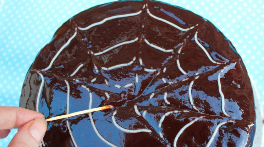 1. Этап. Торт с глазурью: 10. Смажьте торт приготовленной глазурью, затем сливками нарисуйте улитку. Зубочисткой или спичкой протяните от центра до края, нарисовав паутинку.