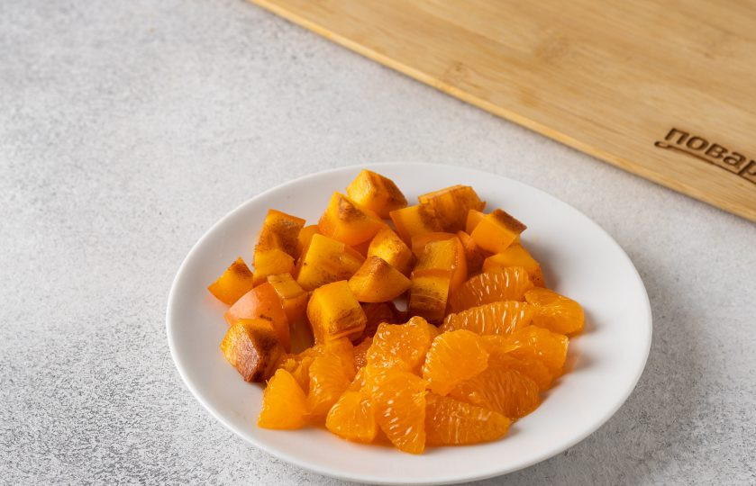 1. Этап. Оранжевый салат с мандаринами и хурмой: Мандарин очистите от кожуры, разделите на дольки и очистите их от белых плёнок. Хурму нарежьте кубиками.