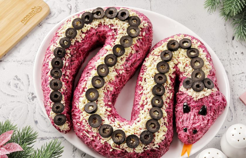 1. Этап. Селедка под шубой на год Змеи 2025: Желтки натрите на мелкой терке и посыпьте змейку сверху полоской. Язык можно вырезать из вареной моркови. Глаза сделайте из маслины. Так же маслины можно нарезать колечками и использовать сверху для украшения. 