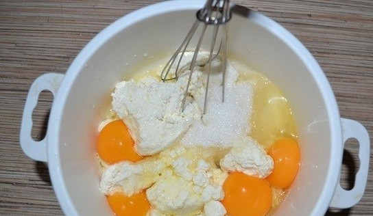 1. Этап. Сырники без муки в духовке: 1. В миску кладу творог, не перетираю его, вбиваю к нему куриные яйца и кладу сахарный песок. Перемешиваю все венчиком.