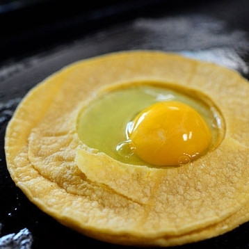 1. Этап. Яичница в тортилье: Аккуратно разбиваем в центр лепешек яйцо.