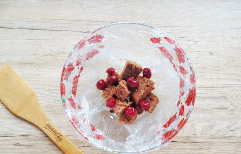 1. Этап. Торт Ай-Петри с вишней: В глубокую миску постелите пищевую пленку так, чтобы края её свисали. Сметану смешайте с сахарной пудрой. Несколько столовых ложек сметанного крема отложите. Две столовые ложки крема выложите на дно формы. Добавьте кубики коржа, измельченные грецкие орехи и вишню без косточек.