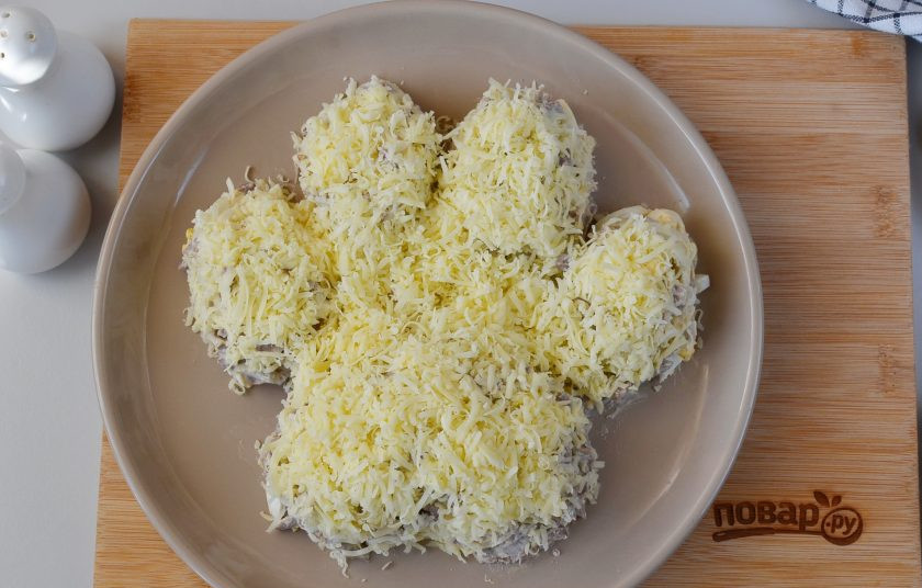 1. Этап. Салат Лапа тигра: Сделайте слой тертого сыра, повторяя контуры лапы, имитируя шерсть тигра (с внутренней стороны она светлая).