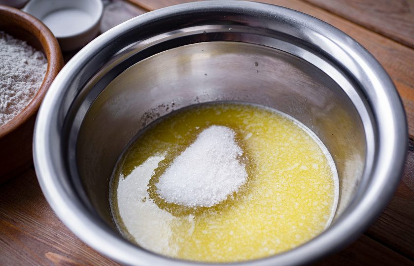 1. Этап. Тесто на топленом молоке: За это время приготовьте сдобную смесь. В чистую миску залейте, растопленное в сотейнике на маленьком огне, сливочное масло, добавьте оставшийся сахар, ванильный сахар и все перемешайте венчиком.