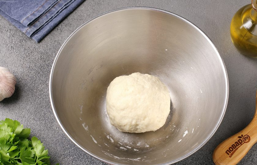 1. Этап. Ароматные чесночные лепёшки: Затем, когда тесто немного остынет, подсыпая частями оставшуюся муку, продолжите замес руками. Накройте тесто полотенцем и дайте полежать 10 минут.