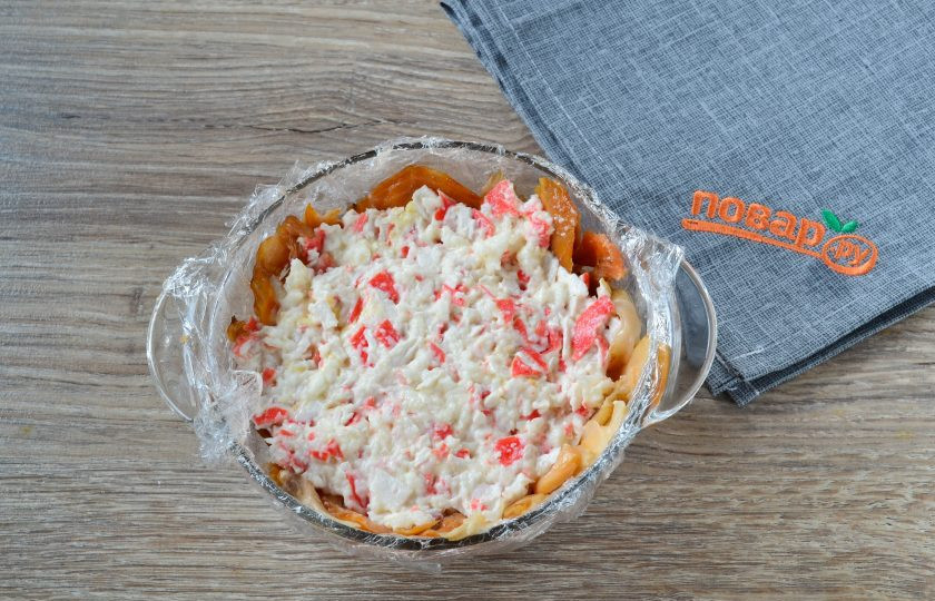 1. Этап. Закусочный торт с крабовой начинкой: Следующим слоем выложите начинку из крабовых палочек.