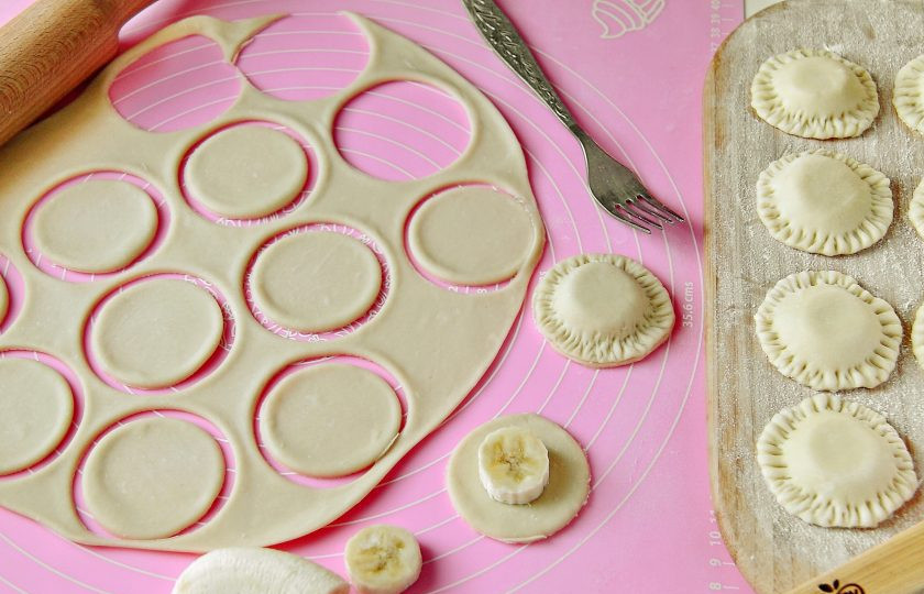 1. Этап. Банановые вареники: Бананы нарежьте кружочками. От теста отрежьте кусок и тонко раскатайте его на присыпанной мукой поверхности. Вырежьте стаканом круги подходящего под банан размера (примерно на 1 см шире со всех сторон). В центр кружка положите банан, накройте его еще одним кружком теста и защипните края при помощи вилки.