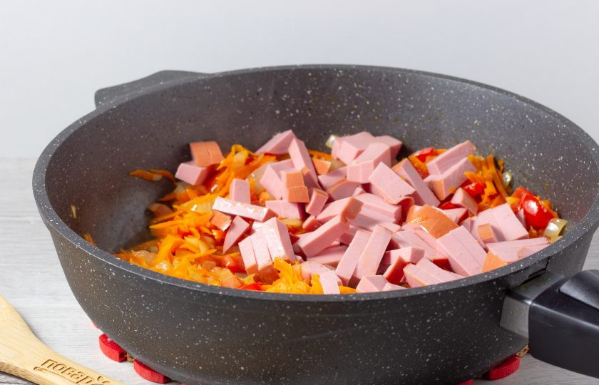 1. Этап. Поджарка из колбасы: Далее добавьте к овощам нарезанную брусочками колбасу. Обжарьте 4-5 минут.