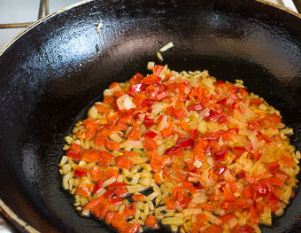 1. Этап. Кускус с грибами: 3. На сковороду налейте немного растительного масла и разогрейте его на среднем огне. Очистите лук и нарежьте мелкими кубиками. Отправьте на сковороду и обжарьте 2-3 минуты. За это время очистите от семян и измельчите перец. Добавьте к луку и продолжайте обжаривать, периодически помешивая.