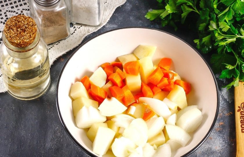 1. Этап. Тыква с овощами: Нарежьте тыкву и картофель крупными кубиками, морковь — средними, а лук — полукольцами. Перемешайте нарезки в глубокой емкости, посолив и сбрызнув растительным маслом.