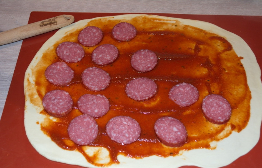 1. Этап. Супер-пицца: Тесто покрыть томатной пастой, выложить тонко нарезанную колбасу.