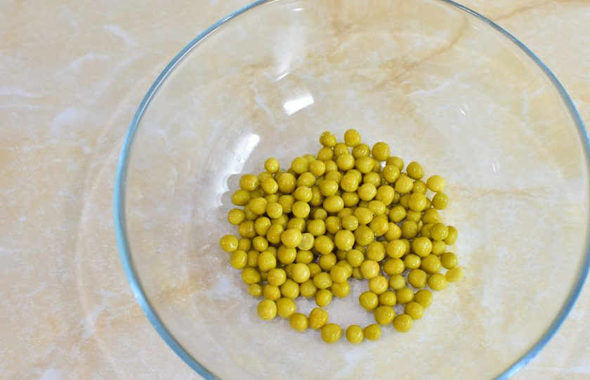 1. Этап. Тарталетки с салатом Оливье: Откройте баночку с консервированным горошком и слейте с него жидкость. Горошек пересыпьте в чашу для приготовления салата.