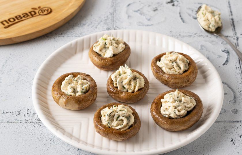 1. Этап. Шампиньоны с творожным сыром и зеленью: Заполните шляпки шампиньонов начинкой из творожного сыра. Можно отсадить начинку с помощью кулинарного шприца.