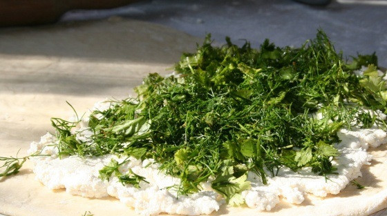 1. Этап. Пирог с творогом и зеленью: 3. Тесто раскатать на присыпанной мукой поверхности. Выложить творог и распределить по всей поверхности. Зелень вымыть, просушить и нарезать мелко. Чем больше зелени, тем сочнее будет пирог. Выложить измельченную зелень на творог.