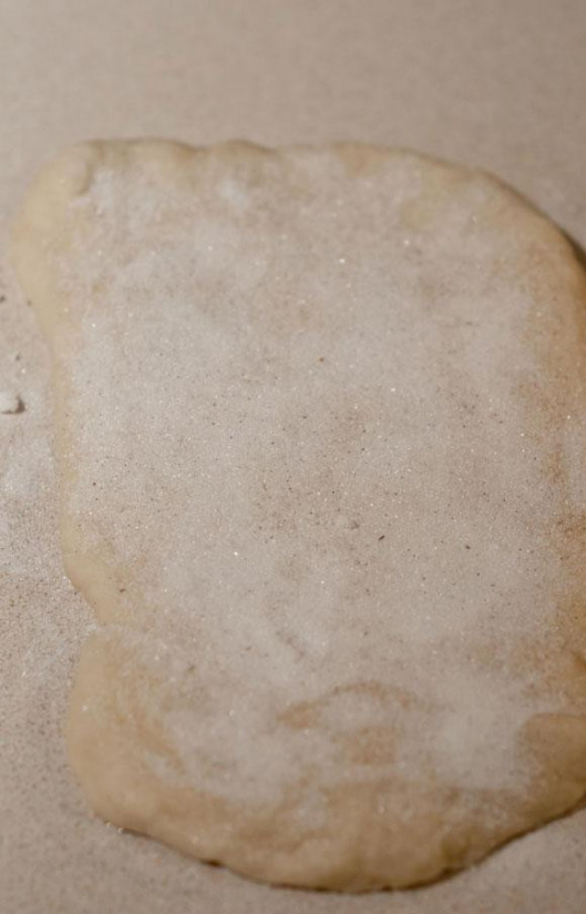 1. Этап. Ванильный хлеб: 3. Выложить тесто на рабочую поверхность и раскатать в прямоугольник размером 30Х45 см. Смазать тесто молоком, оставляя границы по внешнему краю 2,5 см. Посыпать тесто ванильным сахаром.