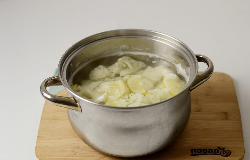 1. Этап. Постный салат с цветной капустой: Половину лимона нарежьте на кружочки. Вскипятите с лимоном воду, добавьте цветную капусту. Варите 4-6 минут, затем слейте воду.