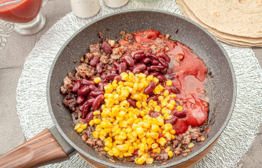 1. Этап. Буррито с фаршем и фасолью: Добавьте фасоль и кукурузу без жидкости, перемешайте и готовьте вместе несколько минут. Посолите и поперчите. Снимите сковороду с плиты, содержимое немного остудите.