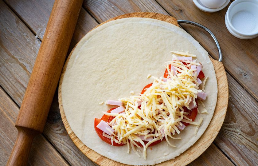 1. Этап. Кальцоне с ветчиной: Натрите сыр на крупную терку и половину распределите поверх ветчины.