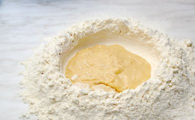 1. Этап. Пельмени из говядины: Муку просеять, сделать лунку, внутрь влить яйцо смешанное с водой и солью.