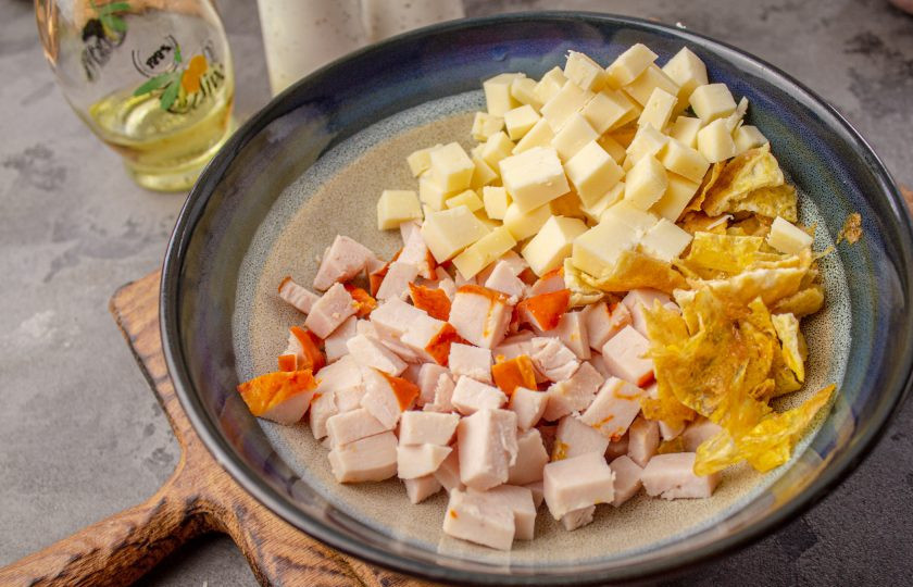 1. Этап. Салат с яичными блинчиками, копчёной курицей и кукурузой: Сыр нарежьте небольшим кубиком. Добавьте его в салатник.