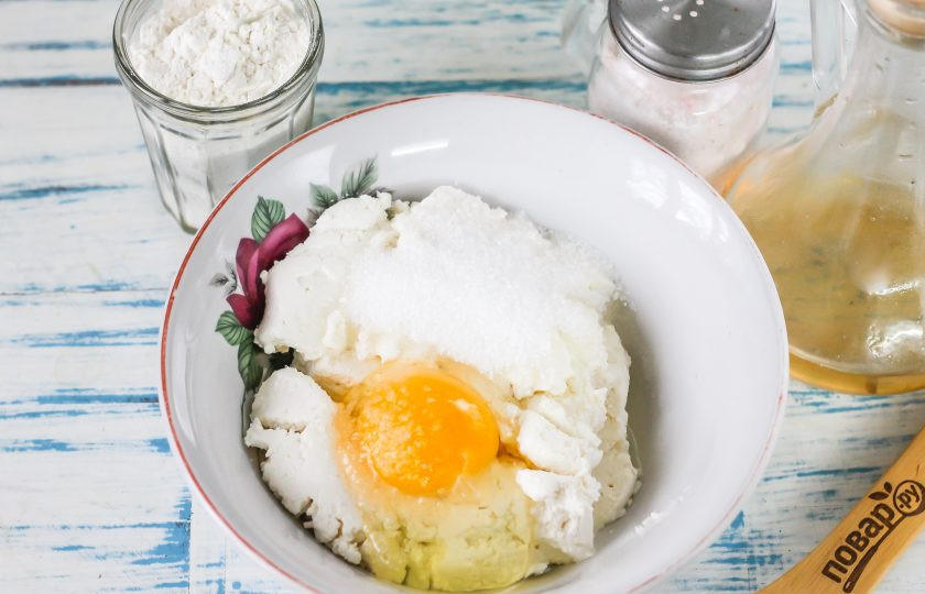 1. Этап. Сырники из козьего творога: Творог выложите в глубокую тарелку или миску, разомните вилкой. Вбейте туда же куриное яйцо, всыпьте сахарный песок, соль. По желанию можете добавить ванильный сахар или пару капель экстракта ванили. Разомните все содержимое емкости.