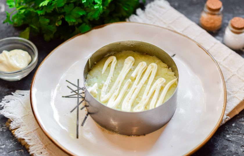 1. Этап. Салат Океан со шпротами: Вареный картофель очистите и натрите на терке. Выложите картофель следующим слоем. Смажьте картофель майонезом.