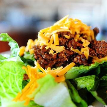 1. Этап. Салат Чизбургер: 5. Выложить листья салата на порционное блюдо. Сверху выложить большое количество мясной смеси, затем большое количество тертого сыра Чеддер.