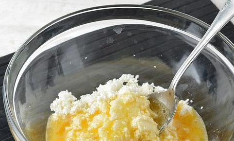 1. Этап. Запеканка из творога на сковороде: В отдельную посуду вбейте два сырых куриных яйца, добавьте к ним сахар. Взбейте яйца с сахаром до однородности, влейте массу в творог.