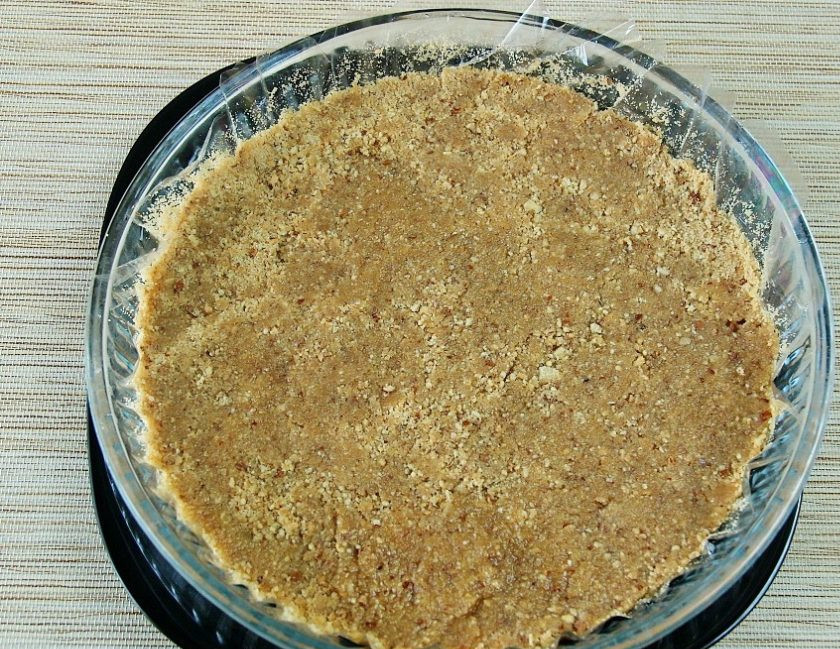 1. Этап. Торт творожный с творожным сыром: Масло влейте к печенью с орехами. Перемешайте тесто. Утрамбуйте его. Уберите основу торта в холодильник на 1,5 часа.