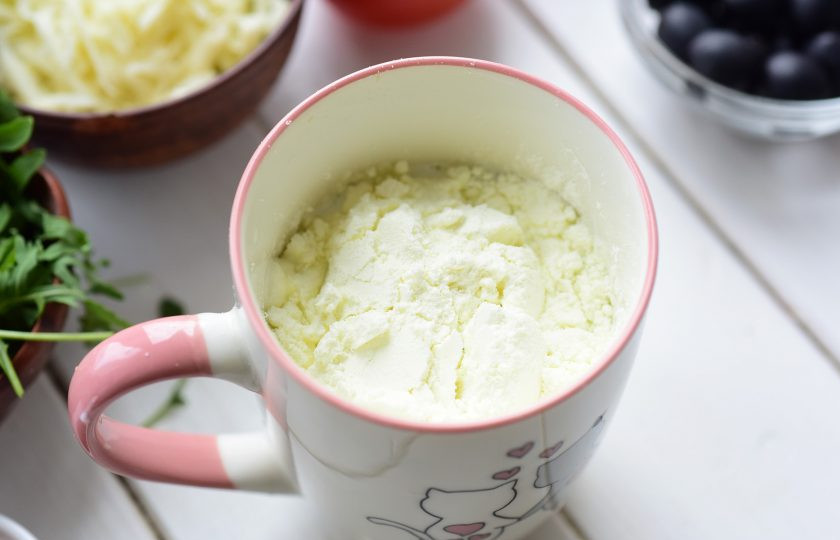 1. Этап. Пицца на сухом молоке: Приготовьте сначала тесто. В кружку залейте теплую воду и добавьте сухое молоко.