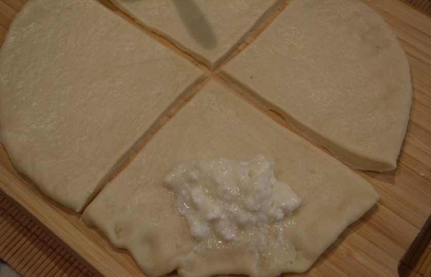 1. Этап. Рожки с творогом в духовке: Смешайте творог с сахаром и 1 яичным белком. Творог слегка пустит сыворотку и станет влажным. Общий пласт теста разрезать на 4-6 частей. На широкий край теста выложите по 1 ч. ложке начинки.
