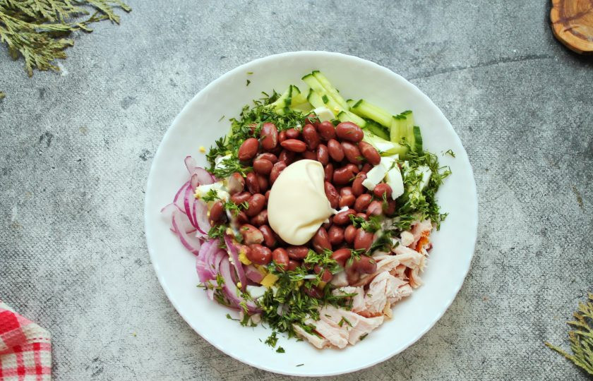 1. Этап. Салат из копченой куриной грудки с фасолью и огурцом: Добавьте в салат фасоль, посолите, заправьте майонезом и перемешайте. Готовый салат разложите порционно и подавайте к столу.