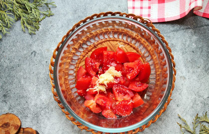 1. Этап. Салат с помидорами, ананасом и сыром: Помидоры порежьте на кусочки и выложите в салатник. Чеснок почистите, измельчите и добавьте к помидорам.