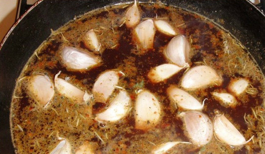 1. Этап. Курица, тушенная с чесноком: Курицу вынимаем пока что и перекладываем в отдельную миску. В сковороду добавляем бульон и немного сухого вина. Сыпем все специи. Можно также добавить щепотку куркумы для аромата. Затем бросаем дольки чеснока. Чистить их не нужно. Доводим смесь до кипения.