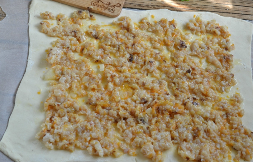 1. Этап. Рулет из рыбы с сыром: Обжарьте сначала лук и морковь в подсолнечном масле, затем добавьте рыбный фарш, посолите и жарьте почти до готовности. Лист слоеного теста раскатайте как можно тоньше (советую это делать на пергаменте, присыпленном мукой), выложите на него подготовленную рыбную начинку.