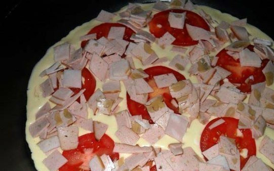 1. Этап. Пицца на сковороде с сыром: 2. Смажьте сковороду растительным маслом и вылейте тесто. Затем выложите помидоры и колбасу.
