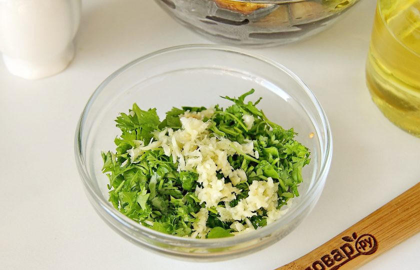 1. Этап. Баклажаны на зиму без уксуса: Зелень измельчите ножом и соедините с пропущенным через пресс чесноком.