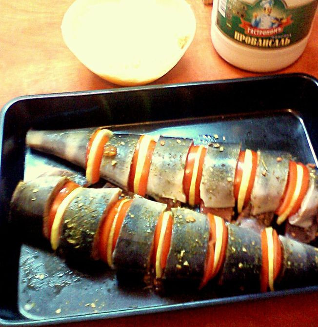 1. Этап. Рыба кижуч, запеченная в духовке: Между кусками филе вставляем нарезанные кольцами помидоры и лимоны. Натираем филе специями и солью.