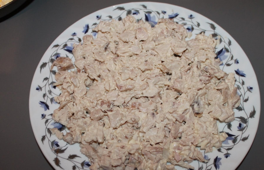 1. Этап. Салат Подсолнух с чипсами: Отварную куриную грудку нарезаем небольшими кубиками. Смешиваем мясо с майонезом и выкладываем на дно салатницы.